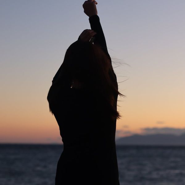 Silhouette of a woman meditating at sunrise, representing well-being.